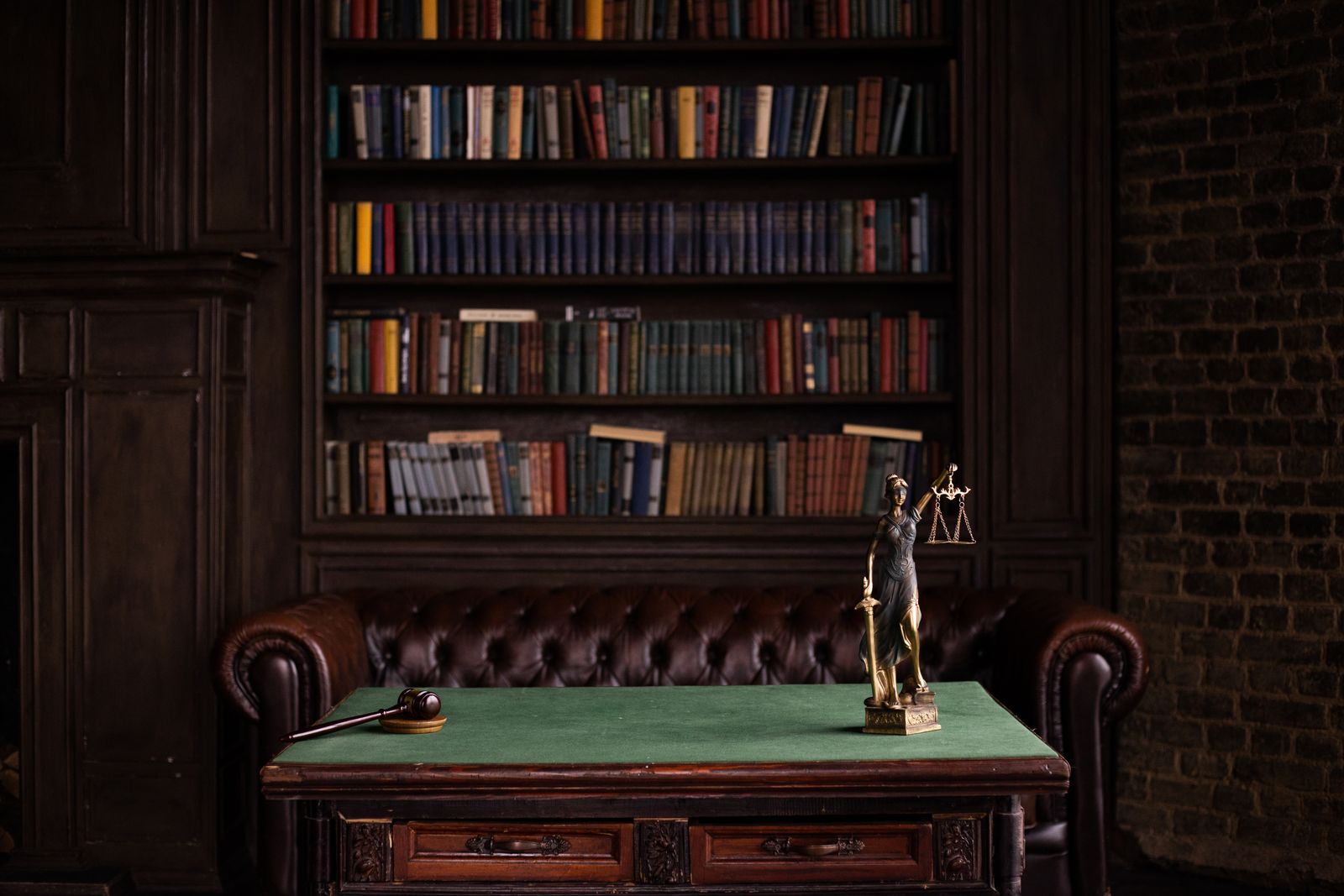 A law library with a leather chair, a desk and a Lady Justice figurine.